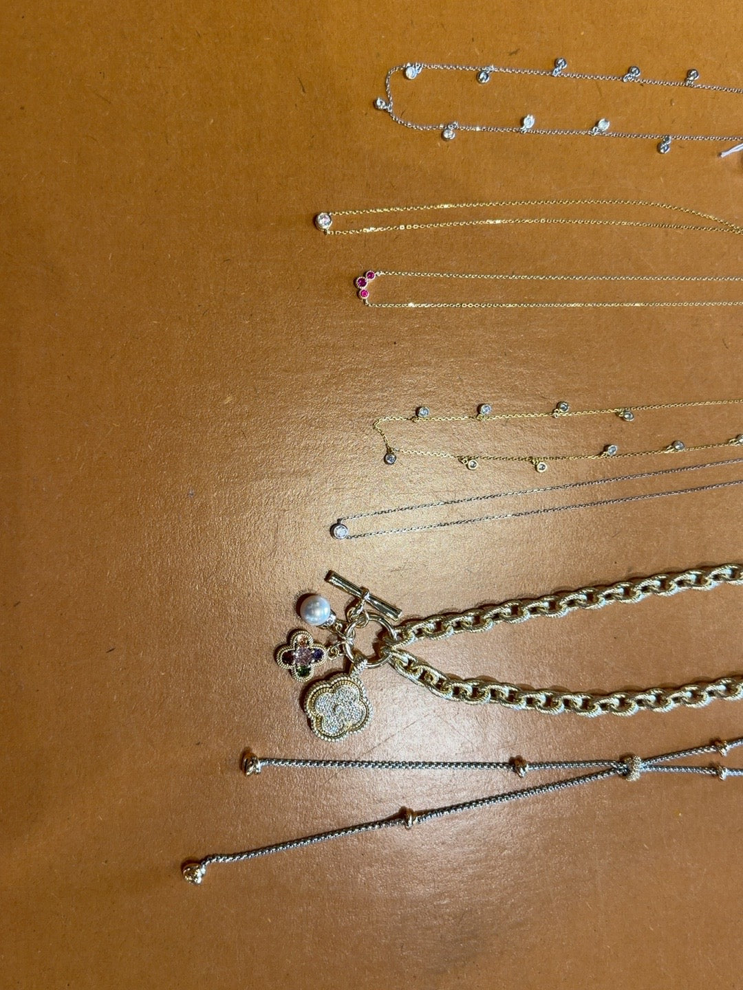 Assorted delicate fine necklaces with crystals, clover charms, and chain details